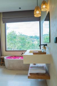 Olea Villas Resort في كوتا لومبوك: حمام مع حوض استحمام و نافذة كبيرة