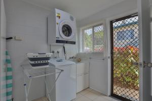 a white kitchen with a sink and a stove at Pacific Sun Bargara in Bargara