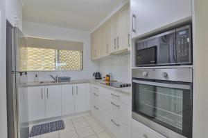 a kitchen with white cabinets and a microwave at Pacific Sun Bargara in Bargara