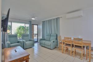 a living room with blue chairs and a dining room table at Pacific Sun Bargara in Bargara