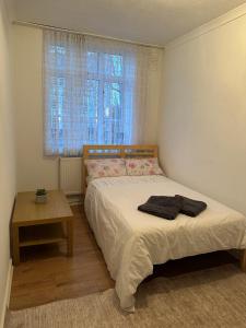 a bedroom with a bed and a table and a window at Spacious Private Room in the heart of Dalston, Hackney in London