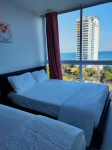 1 dormitorio con 2 camas y ventana grande en Apartamentos en Playa Coronado, en Playa Coronado