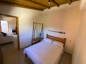 a bedroom with a white bed and a mirror at Chalé do Joca in Ilhabela