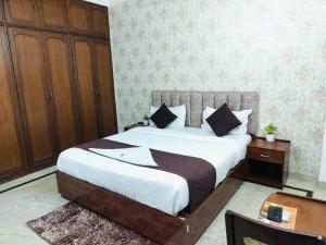 a bedroom with a large bed and a wooden cabinet at Hotel Soft Petal Residency - Delhi Airport in New Delhi