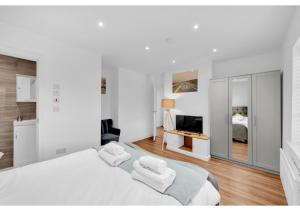 ein weißes Schlafzimmer mit einem Bett und einem TV in der Unterkunft Classic 2BD Flat in Chelmsford in Chelmsford