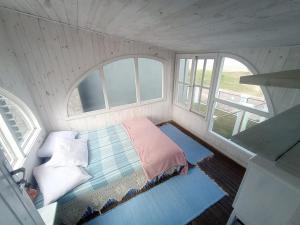 een kleine kamer met een bed en 2 ramen bij Casa beiramar, solar, barulho do mar, pé na areia! in Xangri-lá