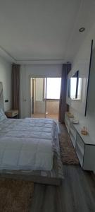 アガディールにあるAppartement 5 etoiles agadir vue merの白いベッドルーム(大型ベッド1台、鏡付)