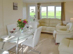a living room with a glass table and white chairs at Roses Place in Bacton