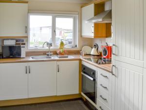 a kitchen with white cabinets and a sink and a window at Roses Place in Bacton