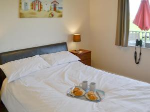 a bed with a tray with two plates of food on it at Roses Place in Bacton