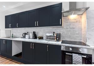 cocina con armarios negros y microondas en Chic 1BD Apartment in Chelmsford, en Chelmsford