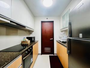 a kitchen with a red door and a black refrigerator at Luxury 2BR with Balcony Suite 25 - Pool, City View in Manila