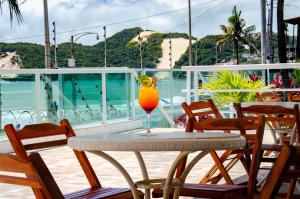 - une table avec une boisson sur le balcon dans l'établissement Suíte PÉ NA AREIA com PISCINA, WIFI e ESTACIONAMENTO em PONTA NEGRA, à Natal