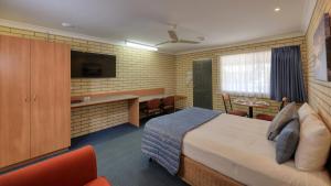 a hotel room with a bed and a desk at Riverland Motor Inn in Saint George