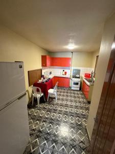 uma cozinha com armários vermelhos e uma mesa com cadeiras em Acogedor Dpto. Con Jardin P.Baja em Cochabamba