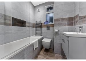 a bathroom with a toilet and a tub and a sink at Captivating 2 BD Flat in London in London