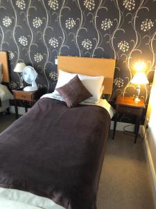 a bedroom with a bed and two tables with lamps at The Noel At Whitwell 