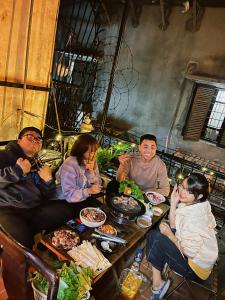 Eine Gruppe von Menschen, die an einem Tisch sitzen und Essen essen. in der Unterkunft GÁC home & decor in Hanoi