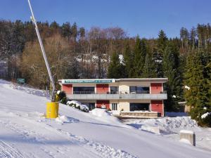 un bâtiment au sommet d'une pente enneigée dans l'établissement Quartier12 "Ski in & Bike out" - Fewo BERG, à Willingen