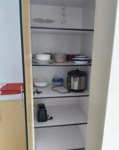 a kitchen pantry with white shelves with dishes at Barrett Accommodation Budget Rooms in Suva