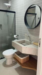 ein Badezimmer mit Waschbecken, Toilette und Spiegel in der Unterkunft VILA CORALLI CASA 05 in Passo de Camarajibe