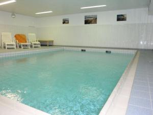 una gran piscina con sillas y una mesa en Norderhoog-Whg-38-1-OG-Wohnung-38, en Westerland