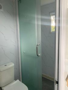 a bathroom with a toilet and a glass shower door at Beachside Bungalows in Batemans Bay