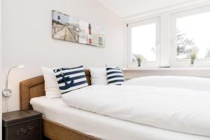 ein weißes Schlafzimmer mit 2 Betten und 2 Fenstern in der Unterkunft Haus Marell 1.OG Wohnung 2 "West" in Wenningstedt-Braderup