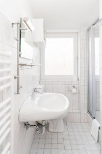 ein weißes Bad mit einem Waschbecken und einem Fenster in der Unterkunft Haus Marell 1.OG Wohnung 2 "West" in Wenningstedt-Braderup