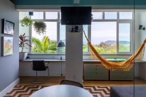 ein Wohnzimmer mit einer Hängematte in einem Zimmer mit Fenstern in der Unterkunft Kit Rio - vista mais linda do RJ in Rio de Janeiro