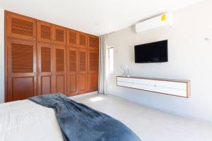 1 dormitorio con 1 cama y TV en la pared en VILLA KUXTAL, en Telchac Puerto