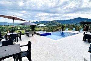 eine Terrasse mit Tischen und Stühlen sowie einem Pool in der Unterkunft Buena vista Casa Quinta con Piscina y Mirador in Carmen de Apicalá