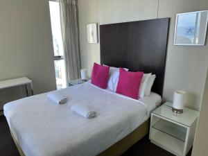 ein Schlafzimmer mit einem großen Bett mit rosa und weißen Kissen in der Unterkunft Deluxe Chevron Renaissance in Gold Coast