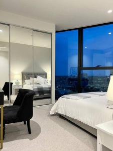 1 dormitorio con 1 cama, 1 silla y 1 ventana en Luxury 3 Bed 2 Bath + car park at Melbourne Square, en Melbourne