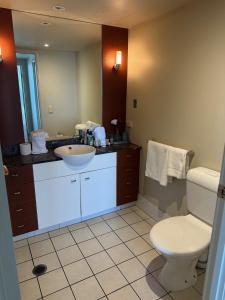 ein Badezimmer mit einem Waschbecken, einem WC und einem Spiegel in der Unterkunft Deluxe Chevron Renaissance in Gold Coast