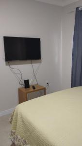 um quarto com uma cama e uma televisão de ecrã plano na parede em Suíte Deluxe em Itajaí