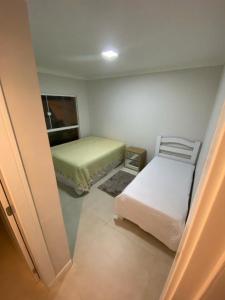 um pequeno quarto com 2 camas e uma janela em Suíte Deluxe em Itajaí