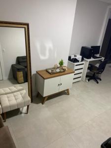 uma sala de estar com um espelho, uma cómoda e uma secretária em Suíte Deluxe em Itajaí