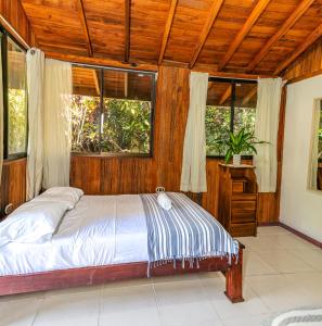 a bedroom with a bed and two windows at Kalea Yard Hotel in Puerto Jiménez