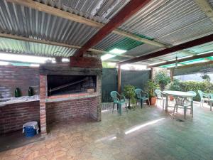 um pátio exterior com uma lareira de tijolos, mesas e cadeiras em Casa grande los tatas em Maldonado