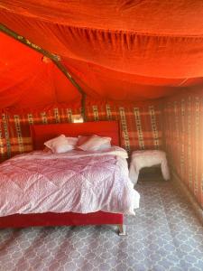 a red tent with a bed in a room at Clouds Desert Camp in Bidiyah