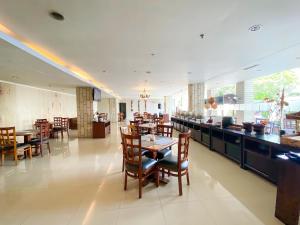 ein Restaurant mit Tischen und Stühlen und eine Bar in der Unterkunft Bueno Colombo Hotel Yogyakarta in Kalasan