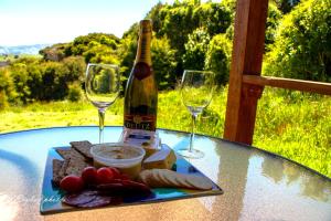 a table with a bottle of wine and two glasses at Glenwood Akaroa Bush Retreat - Kanuka Hut in Akaroa