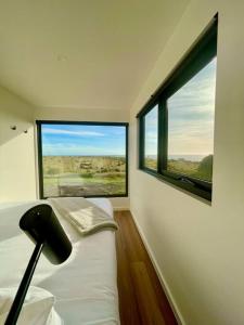 Zimmer mit einem Bett und zwei großen Fenstern in der Unterkunft Bay of Fires Tiny Home in Binalong Bay