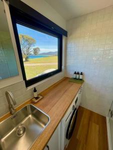eine kleine Küche mit einem Waschbecken und einem Fenster in der Unterkunft Bay of Fires Tiny Home in Binalong Bay