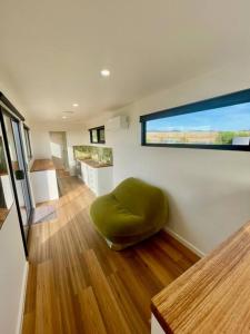 Habitación con reposapiés verde sobre suelo de madera en Bay of Fires Tiny Home, en Binalong Bay