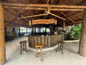 a bar with two stools and a sign that reads reception at Pili Beach Resort Agmanic in Santa Fe