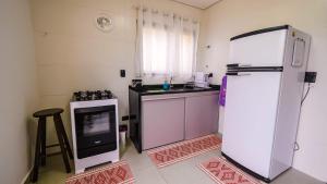 a kitchen with a white refrigerator and a stove at Chalé Amarelo in Itanhaém