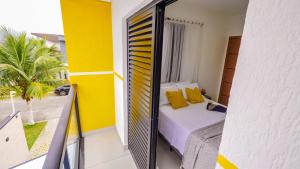a bedroom with a bed and a balcony with yellow walls at Chalé Amarelo in Itanhaém