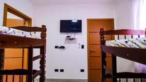 a bedroom with two bunk beds and a tv at Chalé Amarelo in Itanhaém
